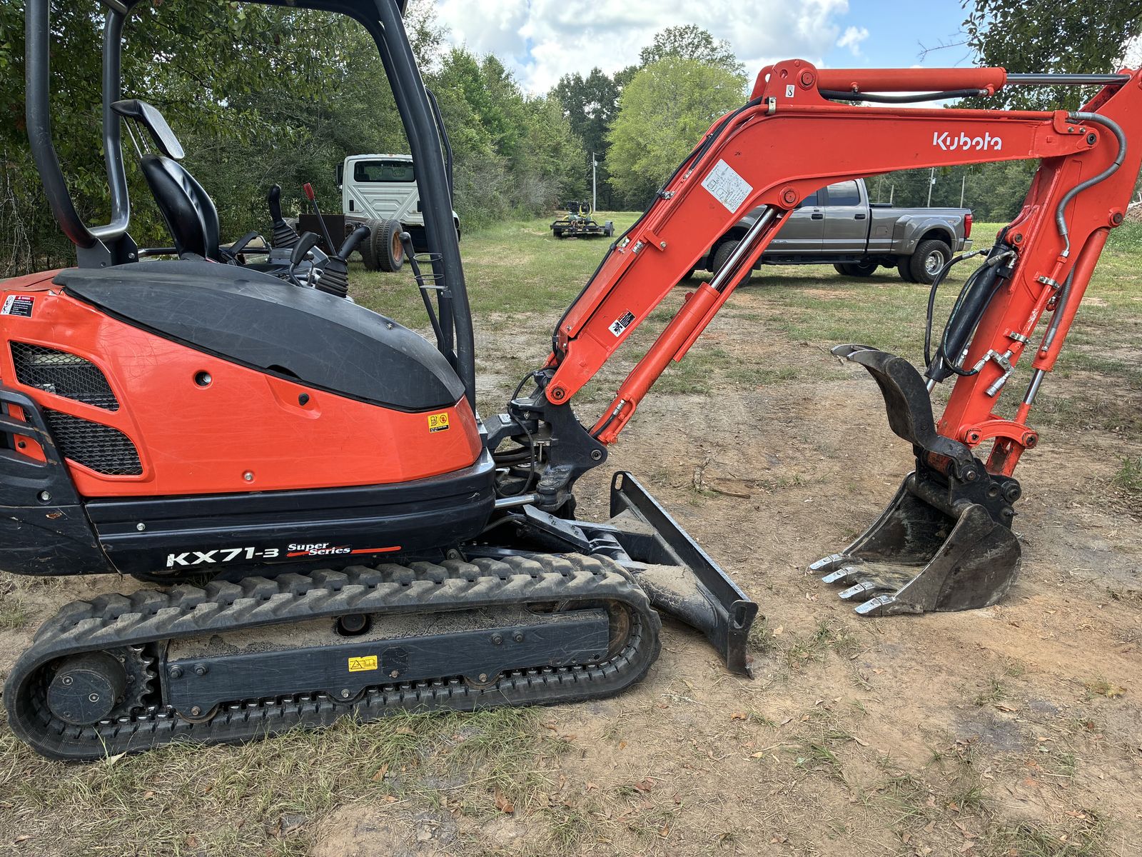 Side view of a Kubota KX71-3 mini excavator with dozer blade and rubber tracks